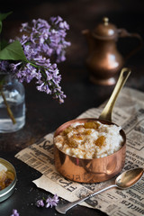 Oatmeal porridge with raisins and cinnamon in a copper cocotte. Oatmeal for breakfast. Vintage style