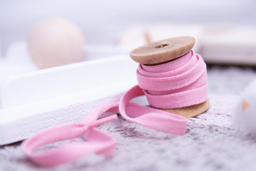 gioco e arredo per bambini, shabby chic, naturale legno, sopra tappeto grigio, rocchetto con laccio rosa