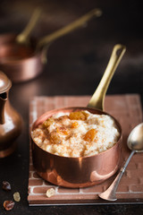 Oatmeal porridge with raisins and cinnamon in a copper cocotte. Oatmeal for breakfast. Vintage style