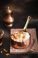 Oatmeal porridge with raisins and cinnamon in a copper cocotte. Oatmeal for breakfast. Vintage style
