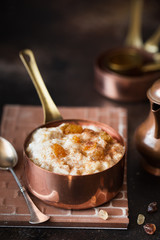 Oatmeal porridge with raisins and cinnamon in a copper cocotte. Oatmeal for breakfast. Vintage style