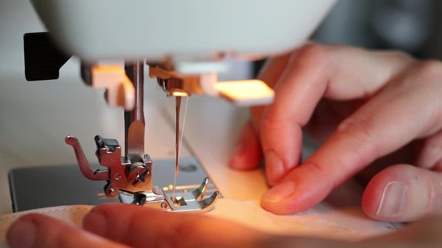 Close up video of woman using sewing machine at home for making protective mask
