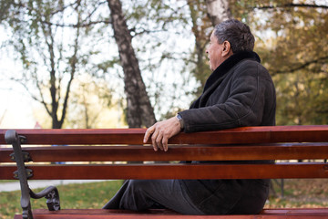 Portrait of happy senior man smiling, in the public park, outdoors. Old man relaxing outdoors and looking away. Portrait of elderly man enjoying retirement