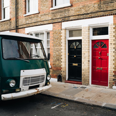 Fototapeta na wymiar Colourful wooden doors and brick building and green old van in Columbia Road, London