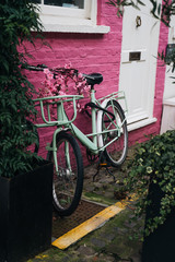 Classic bicycle parked on vibrant pink brick wall in London