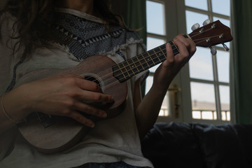 Closed-up ukelele being played by a lady