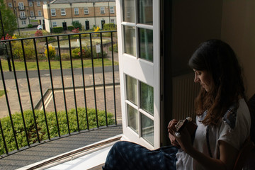 Lady playing the ukelele next to her shiny balcony