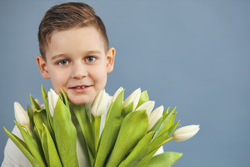 Cute little boy holding a bouquet of flowers. Tulips. Mothers Day. International Women's Day. Portrait of a happy little boy.