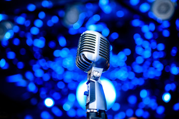 Fototapeta na wymiar Karaoke background.Silver vintage microphone on bokeh.Close-up of retro microphone at concert.Professional microphone 