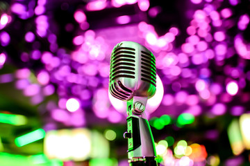 Fototapeta na wymiar Karaoke background.Silver vintage microphone on bokeh.Close-up of retro microphone at concert.Professional microphone 
