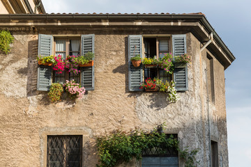 old stone building with wooden shutters and flower pots hanging from the windows