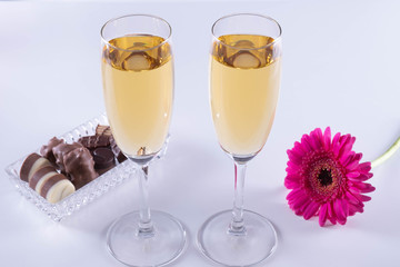 one gerbera flower bud, champagne and chocolate on a table