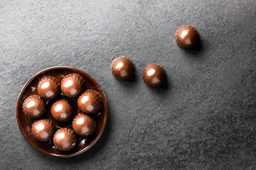 Chocolate candies on a plate on black background with copy space