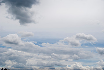 Zdjęcie z miejscem na tekst przedstawiające jasne,  błękitne niebo z chmurami. Jasne i ciemne chmury na tle jasnego nieba.
