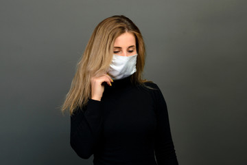 Portrait of a girl in a medical mask, which puts on a rubber glove. Yellow and grey background. Copy space.