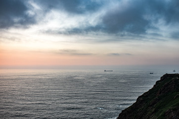 Fototapeta premium Vistas del mar con un barco desde la Campa Torres, Gijón, Asturias, España, al atardecer.