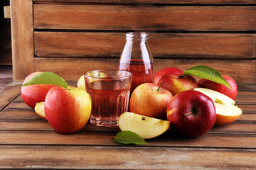 Apple cider drink and organic apples with leaves on table