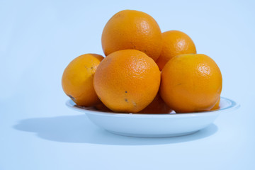 A ceramic dish is full of oranges, juicy fruit and rich in vitamin C, white background.