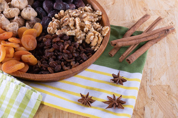 cinnamon, dried apricot, nuts, faygi, dates and raisins in a wooden cup on a tablecloth