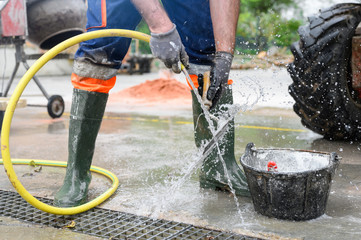 Obraz premium Construction worker washing tools at construction site road street project. Repair, house .