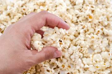 hand takes popcorn from a heap of popcorn. Close-up.