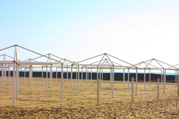 Obraz premium structures for desolate umbrellas and tents of unused bathing establishments alone without quarantine on the beach by the sea