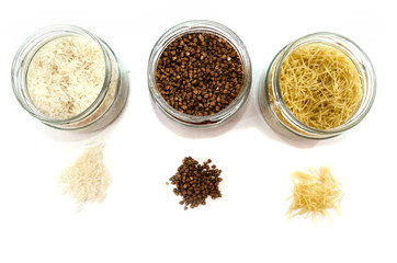 rice, buckwheat and pasta in glass jars on a white background. View from above.