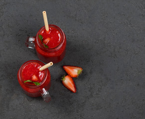 Fototapeta na wymiar Vegan strawberry drink in a jar with a bamboo straw on a dark gray background top view