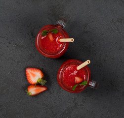 Fototapeta na wymiar Strawberry cocktail in a jar with a bamboo straw on a dark background top view