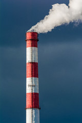 The pipe of the plant emits harmful substances into the atmosphere. Close up on a sky background
