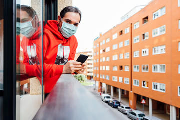 virus man with covid-19 macarilla leaning out of the window using smartphone