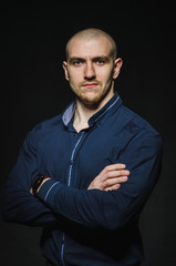 A stylish, bald young man stands on a dark background in the category. Business, Finance