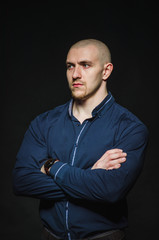 A stylish, bald young man stands on a dark background in the category. Business, Finance