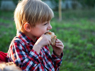 caucasian boy eats a chicken drumstick cooked on the BBQ delicious