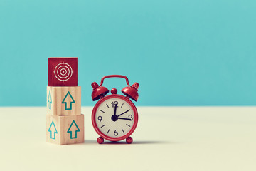 Growth, fall time. Time is money. Lack of time. Time-limit. Business deadline. Stack of wooden cubes and alarm-clock