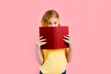 Charming blonde girl in yellow t-shirt posing with exercise books and smiling isolated over pink background.