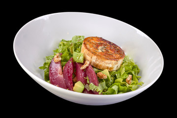 Tasty salad with lettuce, pear and goat cheese, on a plate, isolated on black background