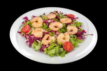 Gourmet shrimp on lettuce and red cabbage on a plate, isolated on black background