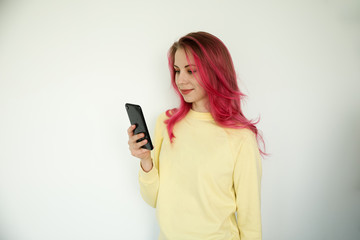 Naklejka premium A young woman on her phone, wearing a yellow shirt on a white background.
