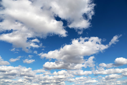 Blue sky covered with white cumulus and cirrus clouds. Spring cloudscape, beautiful weather background
