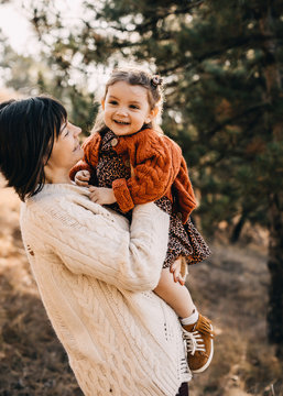 Mother and daughter playing outside on a sunny day. Mother hugging child, having fun together.