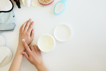 Beauty composition: applying cream to beautiful woman's hands, stylish flowers, moisturizers,...