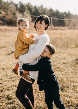 Mother, son and daughter hugging an laughing on golden field background.