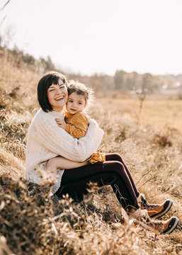 Mother and daughter playing outside on a sunny day. Mother hugging child, having fun together.