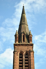 Fototapeta na wymiar Tall Stone Church Spire against Blue Sky seen from Below 