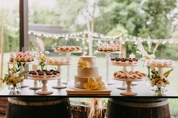 Candy bar at a wedding with different sweets and a wedding cake, in pastel light colors.