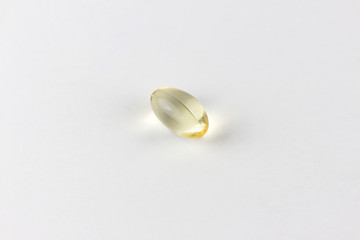 a single gel tab of fish oil or vitamin D or E supplement on a soft white background with copy space