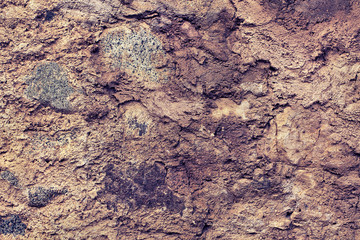Textured stone background. Mountain rock rough surface. Rough background of a limestone quarry with marble inclusions. The natural background of the walls in brown. .