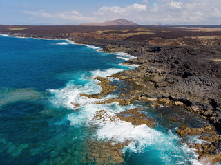 Aerial view of paradisiacal beach with black sand and volcanic scenery in Lanzarote, Canary Islands