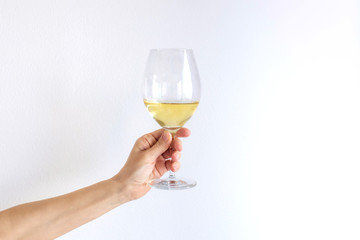 Woman hand holds gives a glass of champagne white wine on a white background. Place for text.